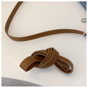 Close-up of brown leather shoulder strap with silver buckle and engraved metal zipper pull