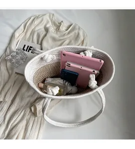Détail macro d'un grand sac cabas tissé avec des essentiels quotidiens sur une robe douce
