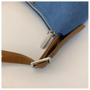 Detail of blue denim fabric with brown leather trim and silver metal zipper pull