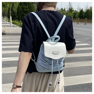 Outdoor shot of a light blue and white pleated mini backpack with a stylish drawstring