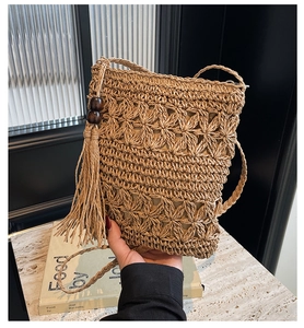 Detailed macro view of woven straw bucket bag with elegant long tassels and brown wood beads