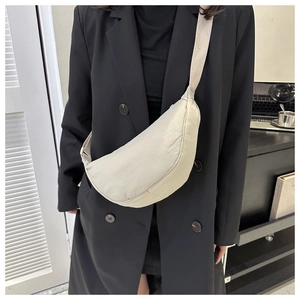 Detailed view of the off-white nylon crescent bag with wide fabric strap and zipper top