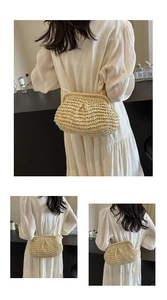 Detail view of woven straw shell bag featuring a sleek gold chain strap on a white dress