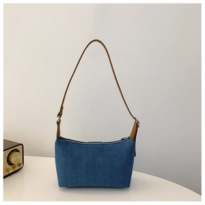 Detail of vintage blue denim shoulder bag with brown leather strap and silver zipper