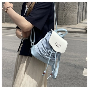Detail of light blue pleated backpack with white faux leather flap and metal clasp
