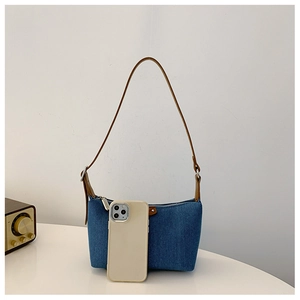 Detail of vintage denim shoulder bag with leather strap and phone for scale reference