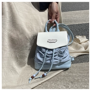 Detail of light blue pleated mini backpack with metal fashion tag and drawstring