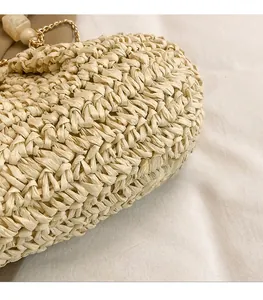 Detailed weave pattern of a beige straw bag with marble beads and gold chain strap