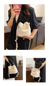 Detail of white drawstring bucket bag with beaded handle and woven shoulder strap