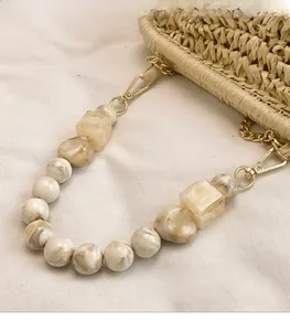 Detail of beaded handbag handle with marble texture resin beads and gold metal hooks
