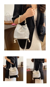 Detail of silver metallic bucket bag featuring large pearl handle and drawstring closure