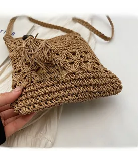 Close-up of brown woven straw bucket bag with geometric hollow patterns and tassels
