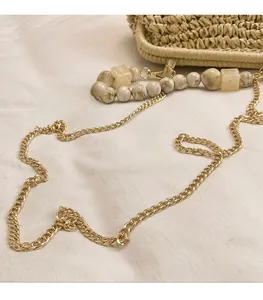 Detail of summer straw bag with marble bead shoulder strap and gold metal chain