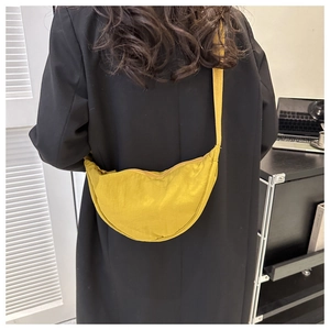 Detailed shot of mustard yellow pleated nylon dumpling bag showing soft fabric texture