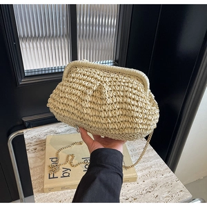 Detail of hand-woven shell straw bag with premium golden chain strap in soft beige