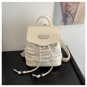 Detail of off-white pleated mini backpack featuring a metal plate and beaded drawstring