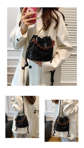 Close-up of black pleated bucket bag featuring unique amber beaded top handle and drawstring