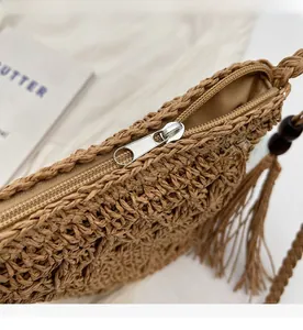 Close-up of smooth metal zipper and tassel detail on woven straw bucket bag