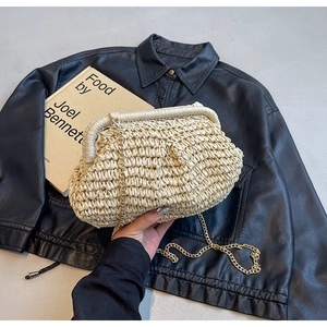 Detail of hand-woven beige straw cloud bag with elegant gold chain strap and metal frame