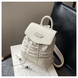 Detail of cream pleated mini backpack with drawstring closure and colorful bead accents