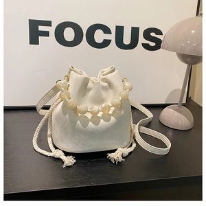 Detailed view of beige bucket bag with pleated texture and beaded pearl handle