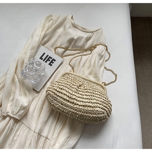 Detail of handwoven cream straw shell bag with elegant gold chain strap for summer