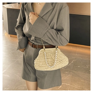 Detail of straw handbag with white pearls handle and gold chain for summer vacation style