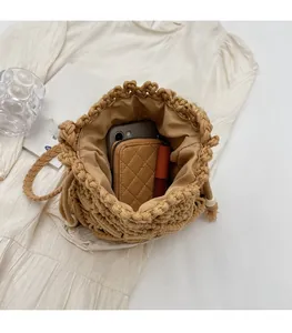 Internal view of hand-woven straw bucket bag showing phone, wallet and drawstring detail