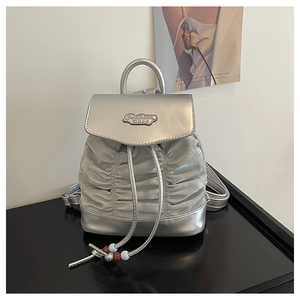 Detail of silver pleated backpack featuring metal Fashion BAG plaque and drawstring closure