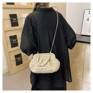 Detail of a straw crossbody bag with marble bead handle and gold chain strap