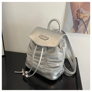 Detail of silver pleated backpack featuring metal Fashion BAG plate and beaded drawstrings