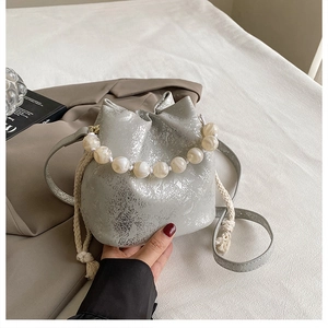 Detail of silver metallic pleated bucket bag featuring a large pearl beaded handle