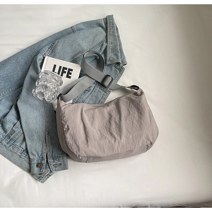 Détail du sac plissé en nylon gris montrant la texture du tissu et la bandoulière