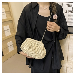 Close-up of woven straw bag with delicate gold chain strap and elegant beige texture