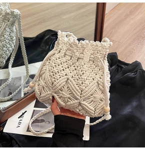 Detailed macro view of cream hand-woven straw bucket bag with drawstring and wooden beads