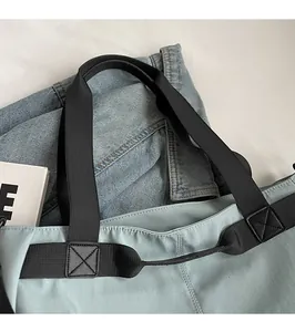 Detail shot of blue canvas tote bag showing reinforced cross stitching and black strap