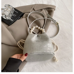 Detail of silver textured bucket bag with white pearl handle and cotton drawstring