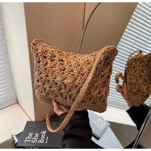 Detailed close-up of handmade woven straw bucket bag with floral hollow patterns and lining