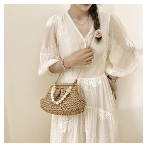 Detail of woven straw bag featuring elegant beaded handle and gold chain shoulder strap
