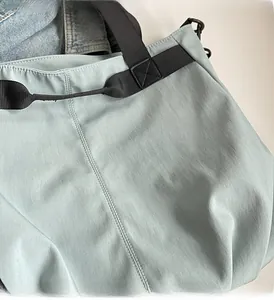 Close-up of mint green canvas tote bag with reinforced black nylon shoulder strap stitching