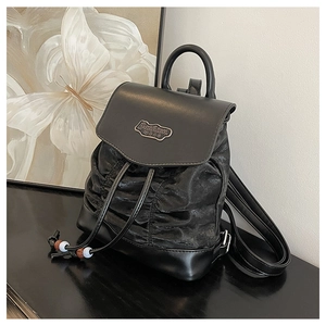 Detail of black pleated PU mini backpack featuring a drawstring closure and metal logo