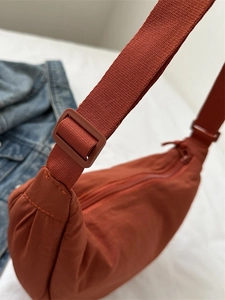 Orange nylon croissant bag with adjustable fabric strap for a casual minimalist look