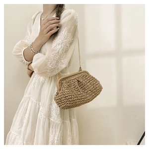 Detailed view of woven straw cloud bag featuring natural texture and gold chain strap