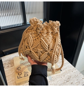 Detail of hand-woven straw bucket bag featuring diamond patterns and white wooden beads