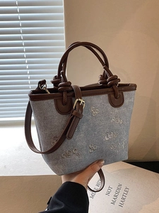 Floral embroidered denim bucket bag with brown leather handles and shoulder strap