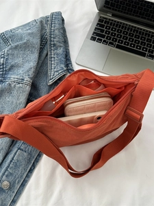 Minimalist orange nylon dumpling bag showing organized interior with pockets for daily items
