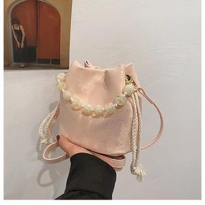 Detail of pink pleated bucket bag with creamy pearl handle and cotton drawstring closure