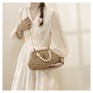 Detail of woven straw bag with marbled bead handle and gold chain strap in natural light