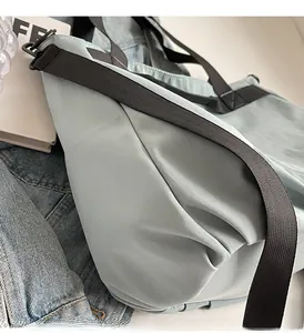 Detail of light blue waterproof nylon shoulder bag with wide black strap and metal buckle