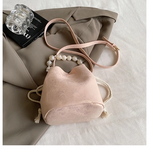 Detail of light pink pleated bucket bag with pearl handle and adjustable shoulder strap